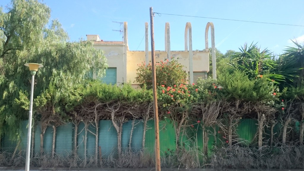 Current status of one of the 3 façades overlooking the street and appearance of one of the sections of the 111 linear-metres-perimeter of the exterior fence up to the beginning of the fence construction works in September of the present year.